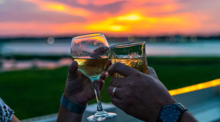 Couple enjoying themselves with drinks while looking at the waterfront.