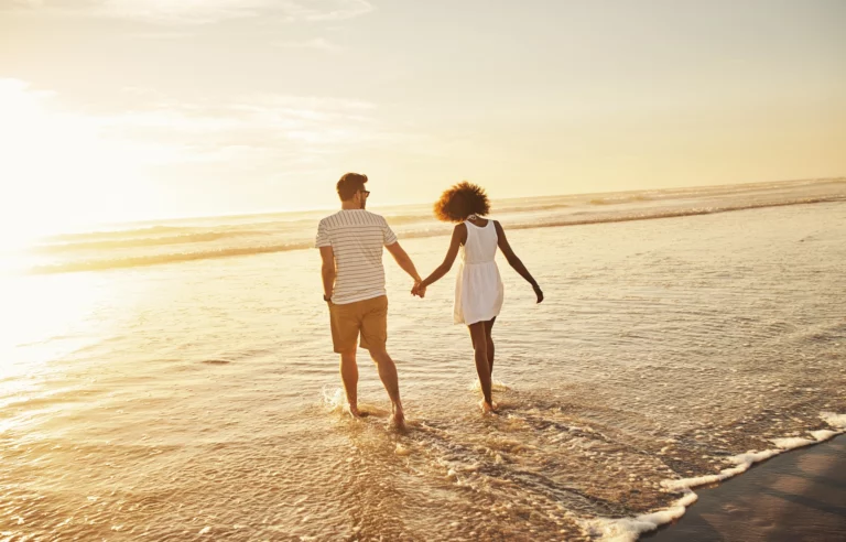 Married couple walking on the beach.