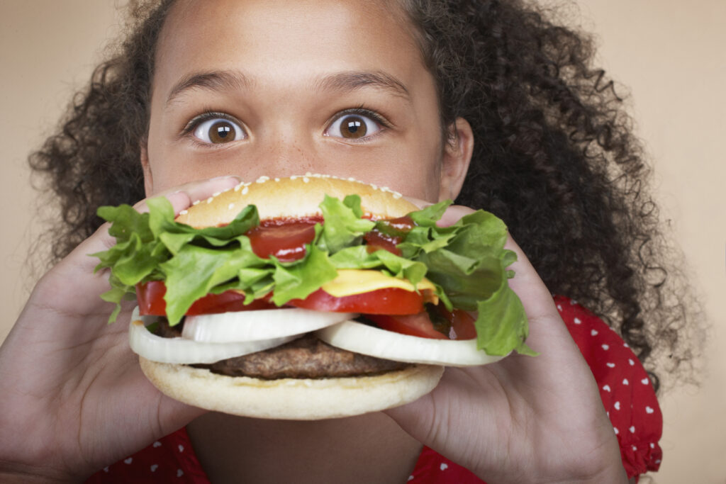 Young girl eating a hamburger.